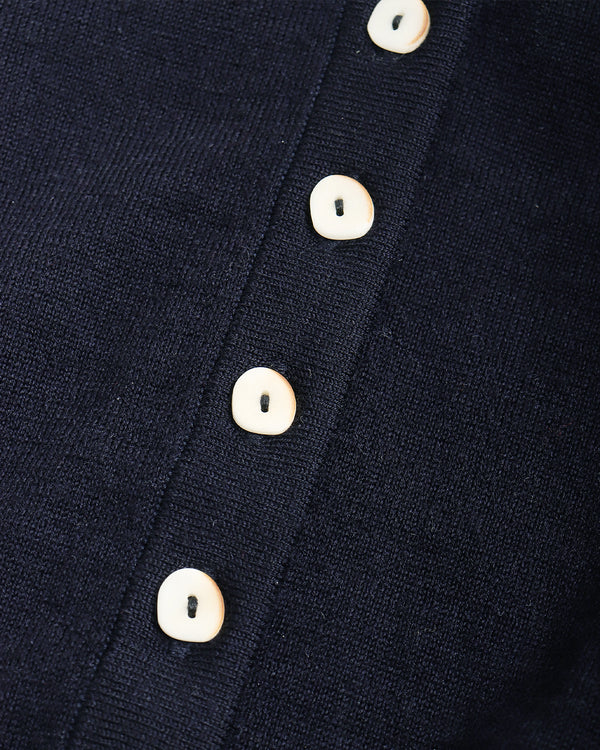 Close-up of a dark navy knit garment with a vertical row of round off-white buttons.