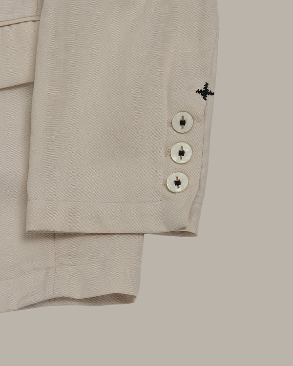 Close-up of blazer sleeves with cross stitching details on a light gray background