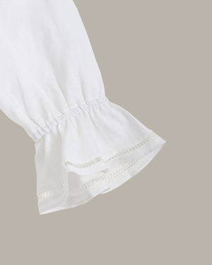 Close-up of a white blouse with ruffled sleeves on a beige background