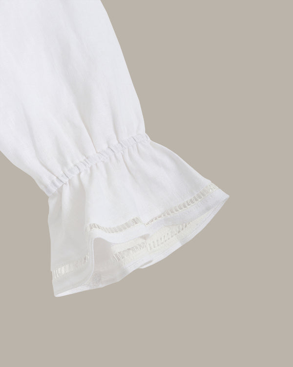 Close-up of a white blouse with ruffled sleeves on a beige background