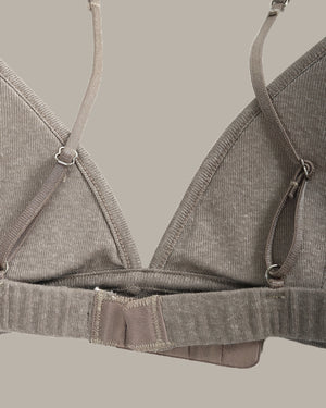 Gray bra on a hanger against a neutral background