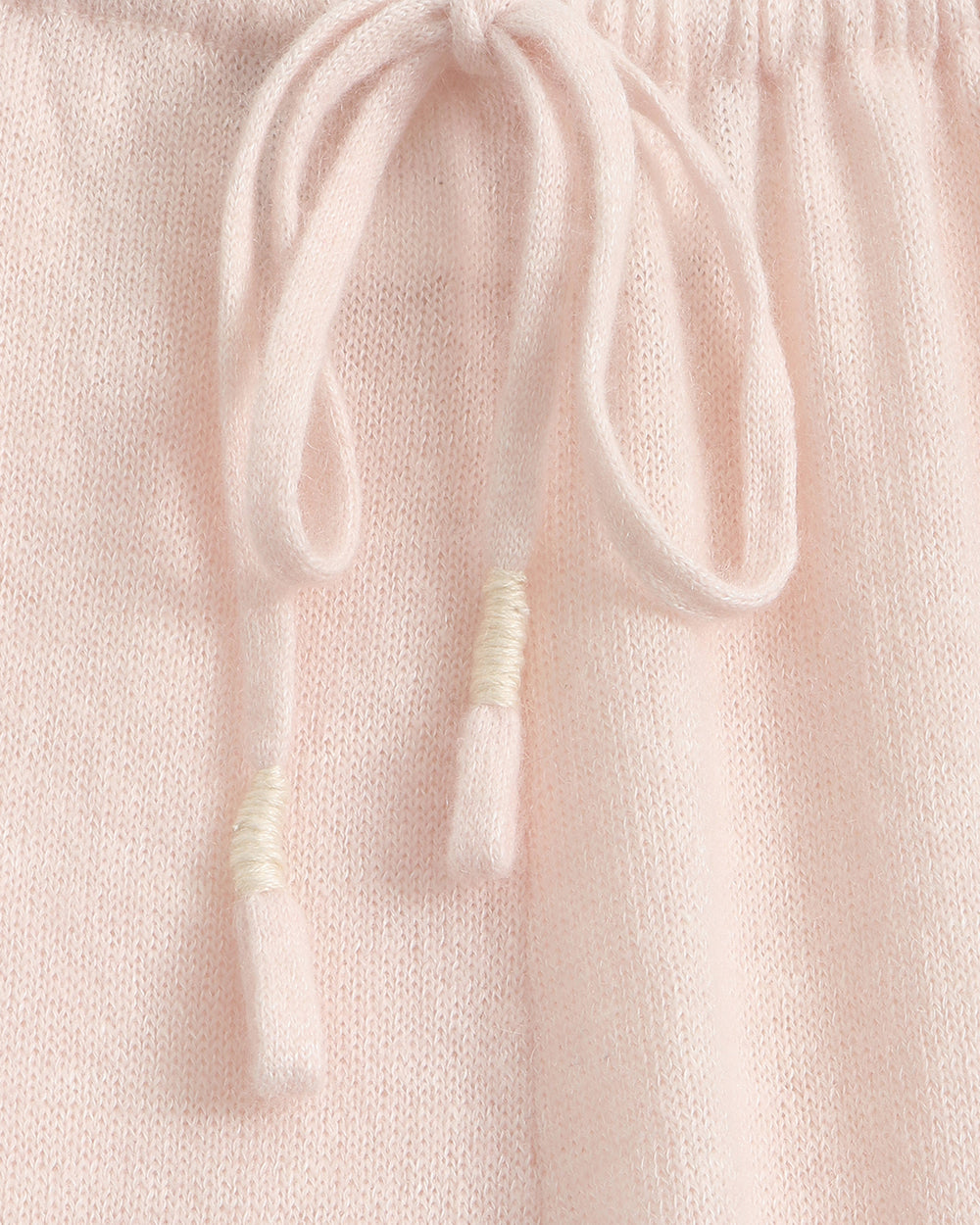 Light pink wide-leg lounge pants with an elastic waistband and drawstring, shown flat against a solid taupe-gray background.