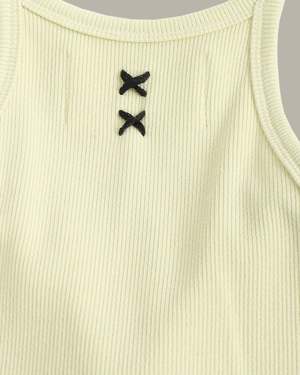 Close-up of a ribbed tank top with black button details on a light green background
