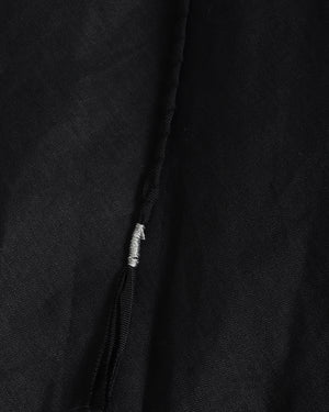 Close-up of a black textured fabric garment with a silver-toned zipper pull.