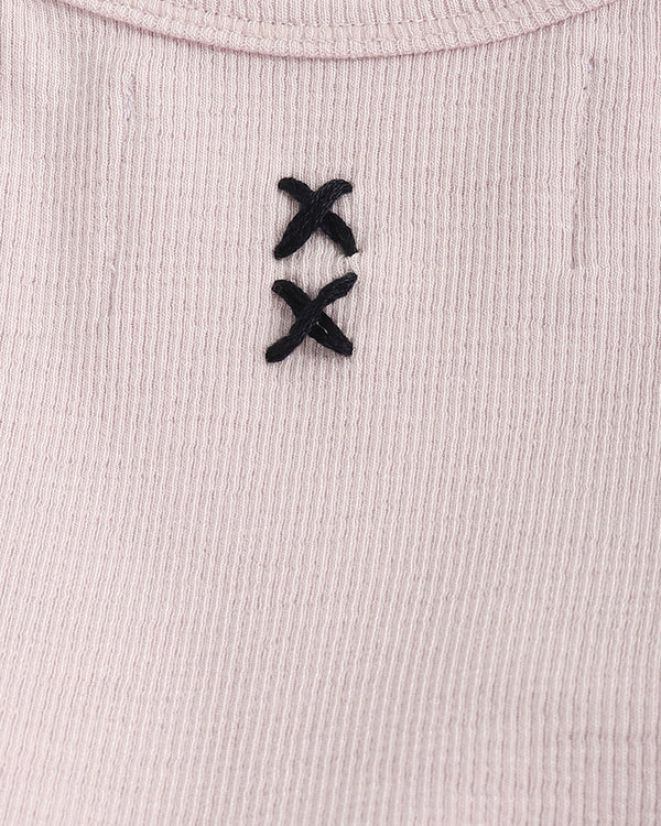 Close-up of a ribbed fabric with black embroidered design on a light pink background