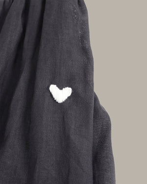 Dark gray fabric with a white heart-shaped patch on a neutral background
