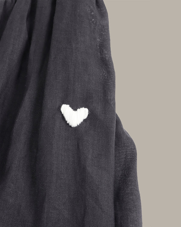 Dark gray fabric with a white heart-shaped patch on a neutral background