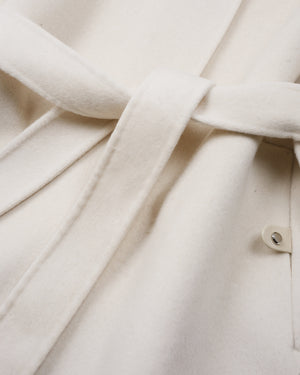 Close-up of an off-white or cream-colored fabric garment with a matching tie belt and a small button detail.