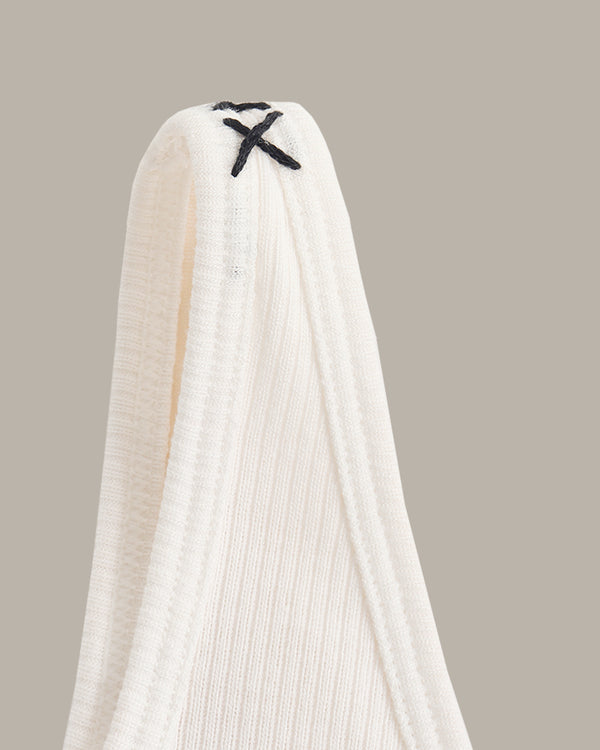 White tank with black straps on a beige background