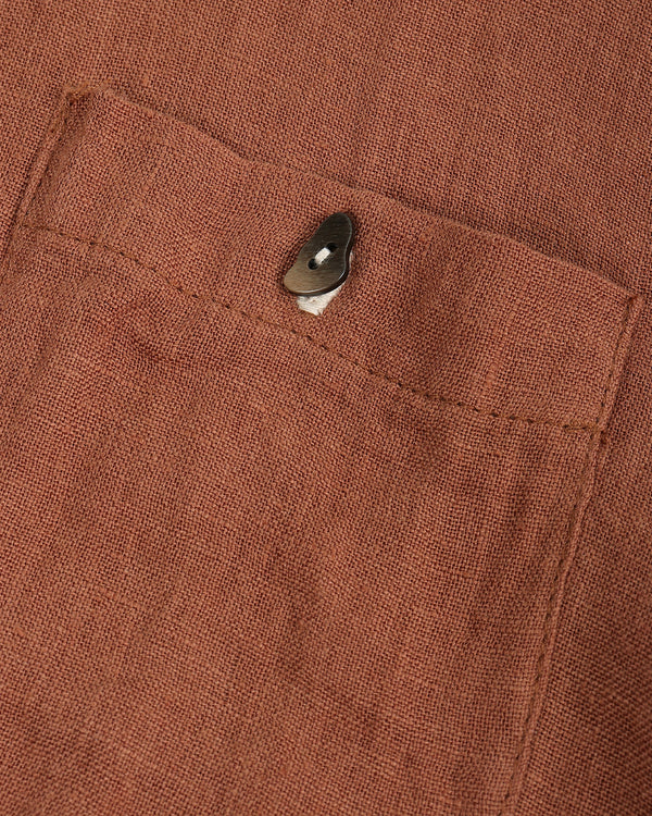 Close-up of a brown fabric pocket with a button on a garment.