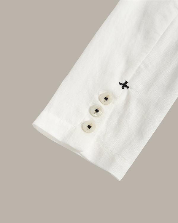 Close-up of a white blazer sleeve with cross stitching on a beige background