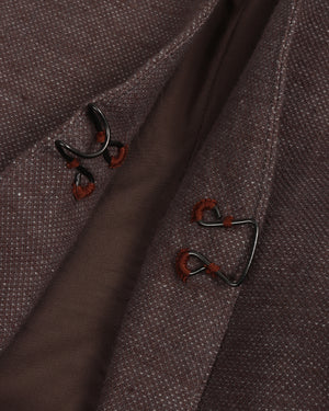 Close-up of a brown fabric with embroidered button designs on a dark background