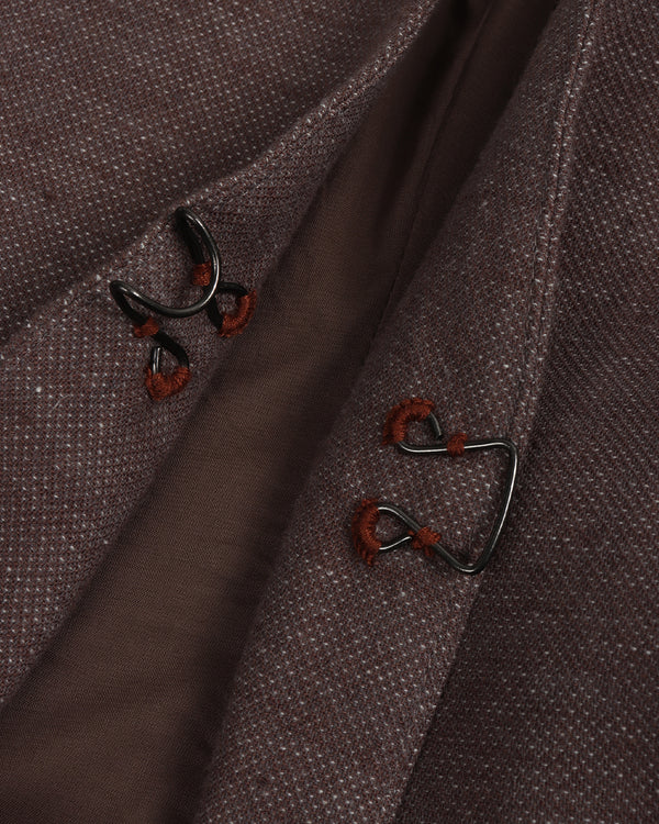 Close-up of a brown fabric with embroidered button designs on a dark background