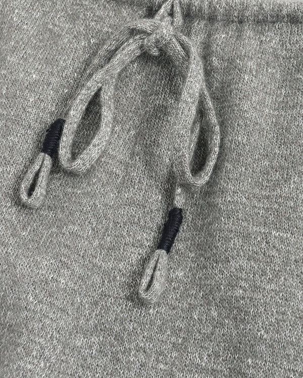Close-up of a gray heathered knit fabric with matching drawstrings and black ribbed accent tips.