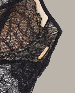 Black lace garment with a gold tag on a gray background