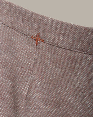 Close-up of a textured fabric with a small red cross stitch on a neutral background