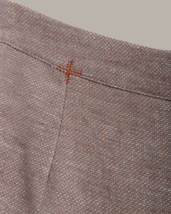 Close-up of a textured fabric with a small red cross stitch on a neutral background
