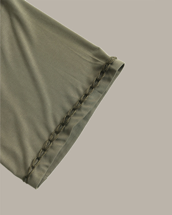 Green fabric with decorative stitching on a gray background