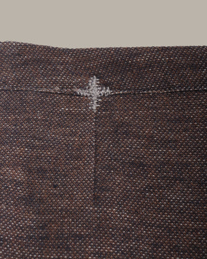Close-up of a textured brown fabric with a subtle pattern and stitching detail.