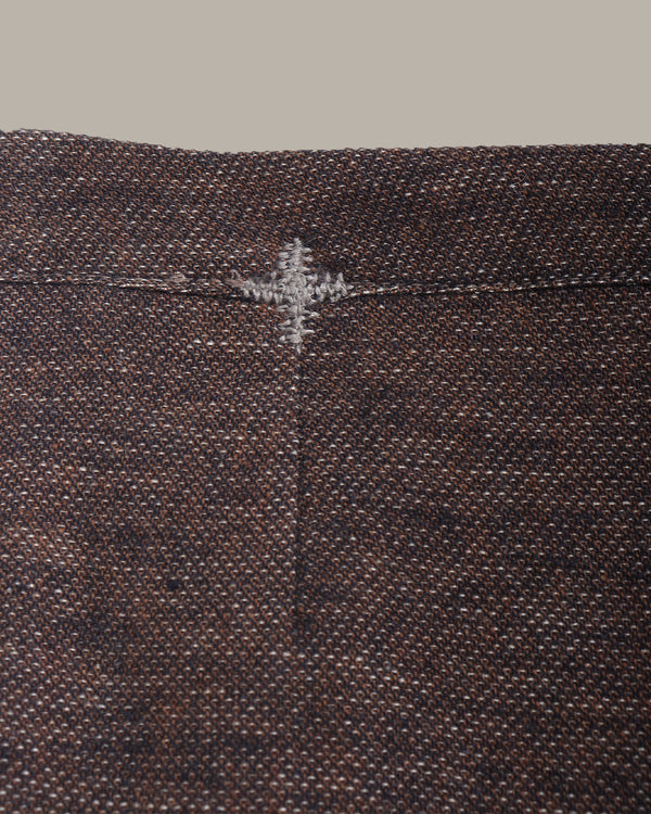 Close-up of a textured brown fabric with a subtle pattern and stitching detail.