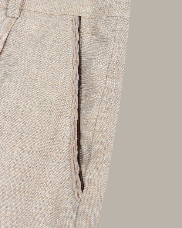 Close-up of beige pants with a subtle pattern on a gray background