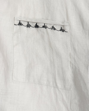 Close-up of a white textured fabric pocket with a black embroidered heartbeat line across the top edge.