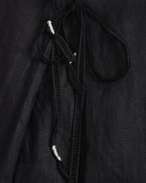 Close-up of a black textured garment with a drawstring detail and small white bead accents.