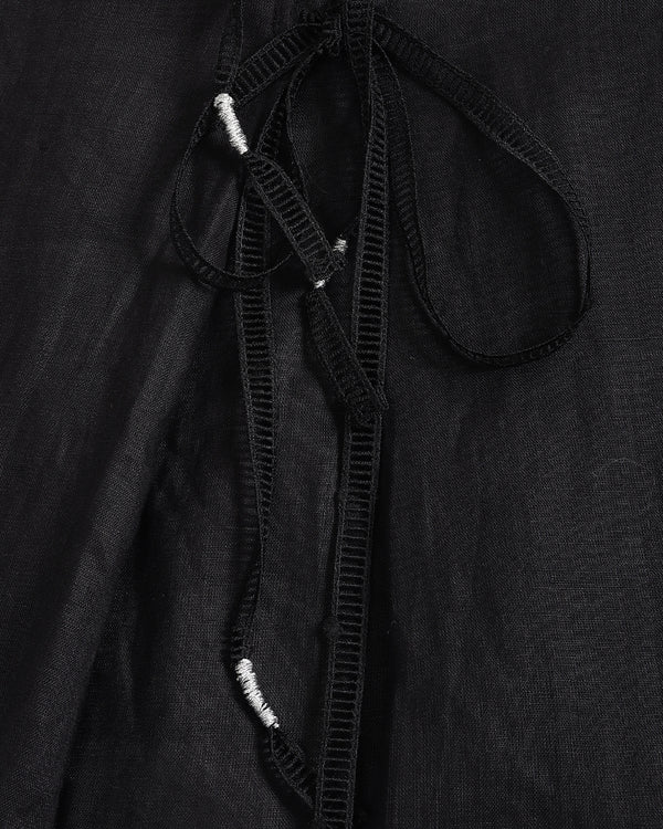 Close-up of a black textured garment with a drawstring detail and small white bead accents.