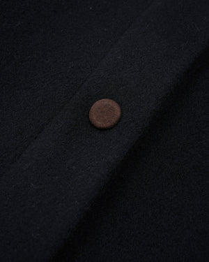 Close-up of a dark navy wool fabric with a single round brown button on the left side.