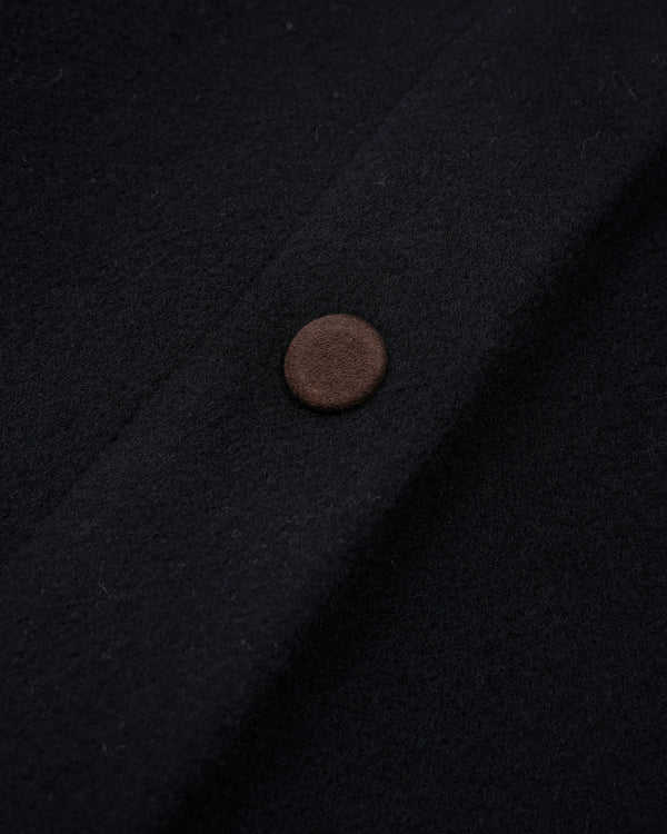 Close-up of a dark navy wool fabric with a single round brown button on the left side.