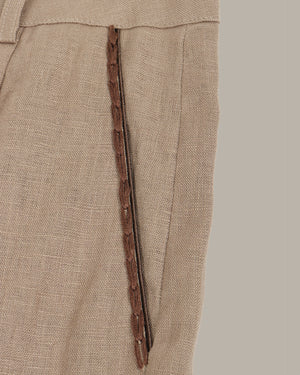 Close-up of brown pants with a decorative pockets on a beige background