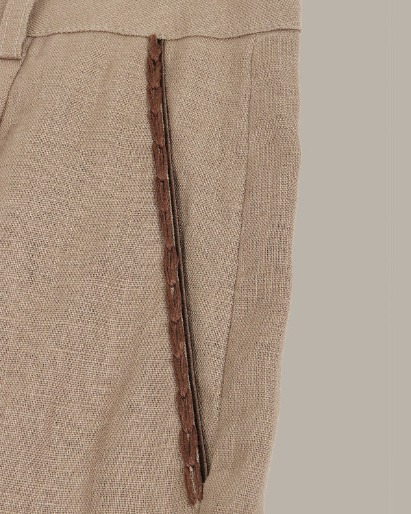 Close-up of brown pants with a decorative pockets on a beige background