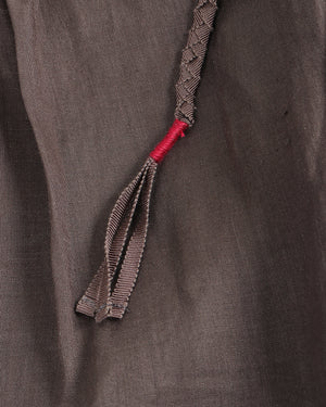 Close-up of a braided cord with a red end on a textured brown fabric background