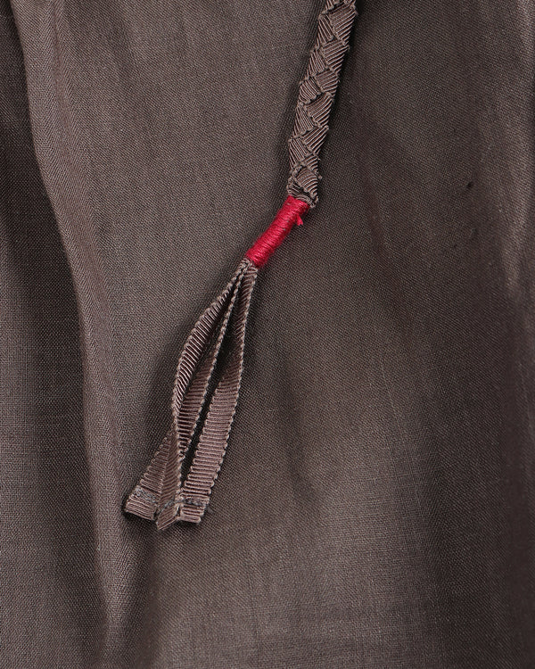Close-up of a braided cord with a red end on a textured brown fabric background