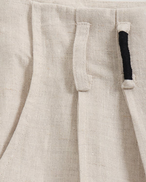 Close-up of beige pants with a pocket and black trim.