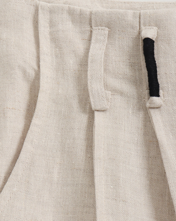 Close-up of beige pants with a pocket and black trim.