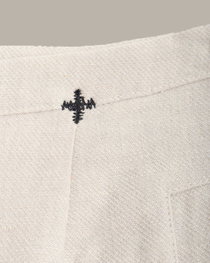 Close-up of a textured fabric with a small embroidered design on a neutral background
