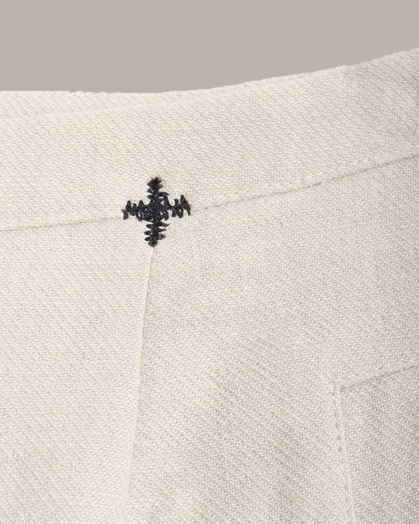 Close-up of a textured fabric with a small embroidered design on a neutral background