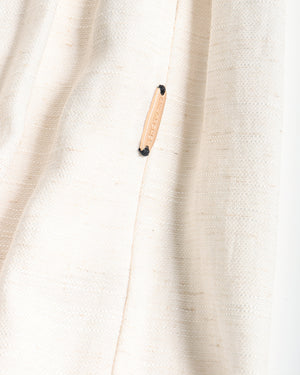 Close-up of a textured off-white pants with a small beige leather brand tab sewn onto the seam. The tab features the brand name 'CHLOECHEN' in black text.