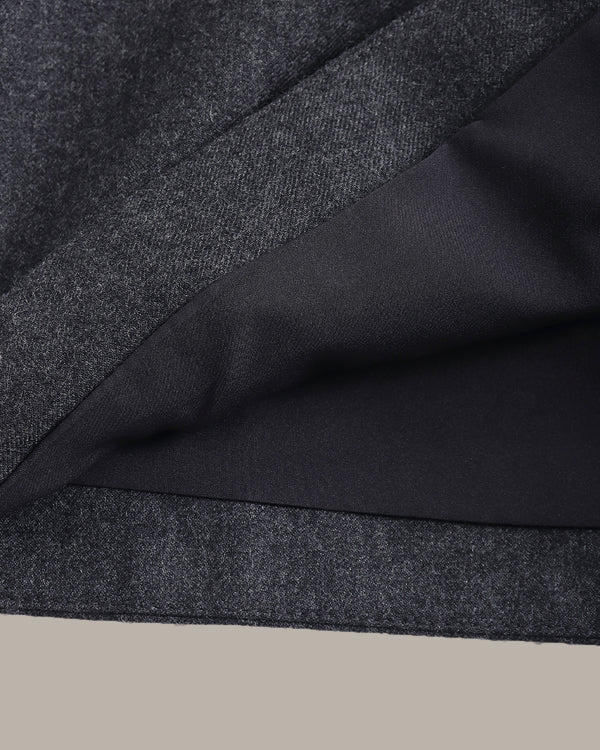 Close-up of a dark charcoal gray textured fabric with a smooth black lining, folded diagonally against a light beige background.