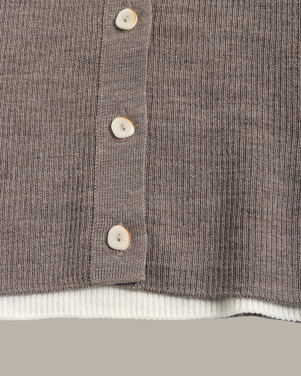 Close-up of a ribbed knit cardigan in taupe-brown with four light beige buttons and a white ribbed hem, shown against a neutral gray background.