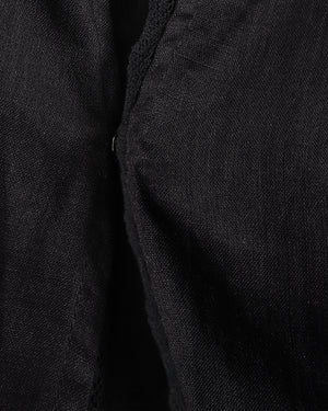 Close-up of a black textured fabric garment, showing a folded edge and fine woven material detail.