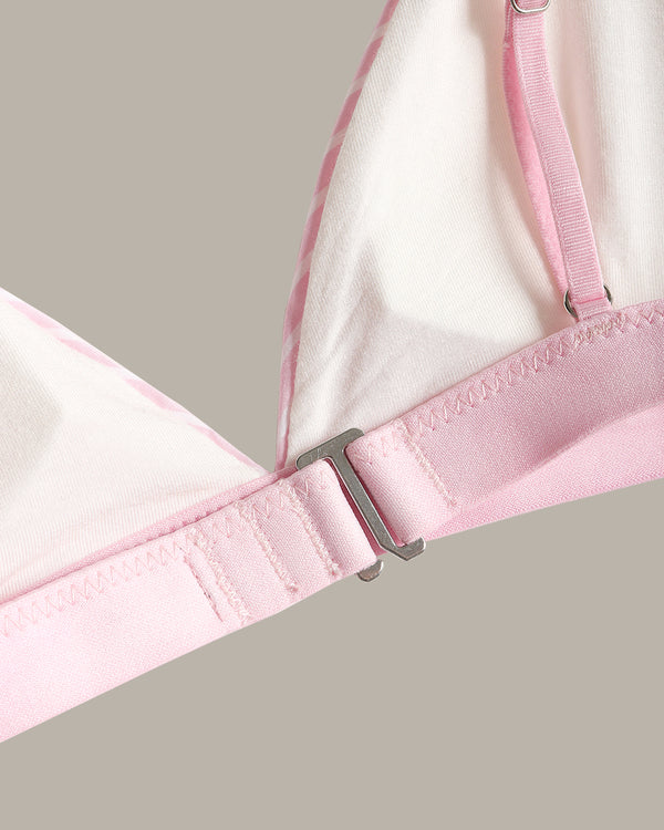 Close-up of a light pink and white bra strap and adjustment buckle detail against a solid taupe background.