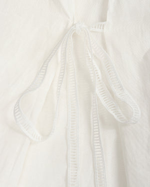 Close-up of a white textured fabric garment with a drawstring tie closure.