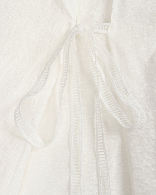 Close-up of a white textured fabric garment with a drawstring tie closure.
