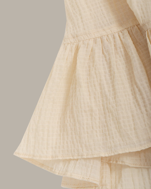 Beige top with a textured fabric on a neutral background