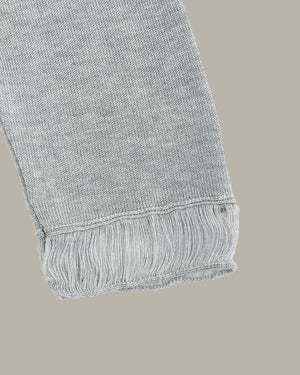 Gray knitted fabric with frayed edge on a beige background