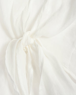 A close-up of draped off-white fabric gathered into a soft knot, showing the material's texture and folds.