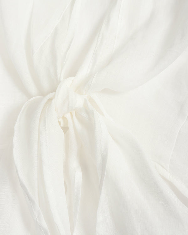 A close-up of draped off-white fabric gathered into a soft knot, showing the material's texture and folds.