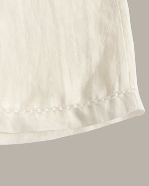 Close-up of a white fabric edge with a subtle pattern on a gray background